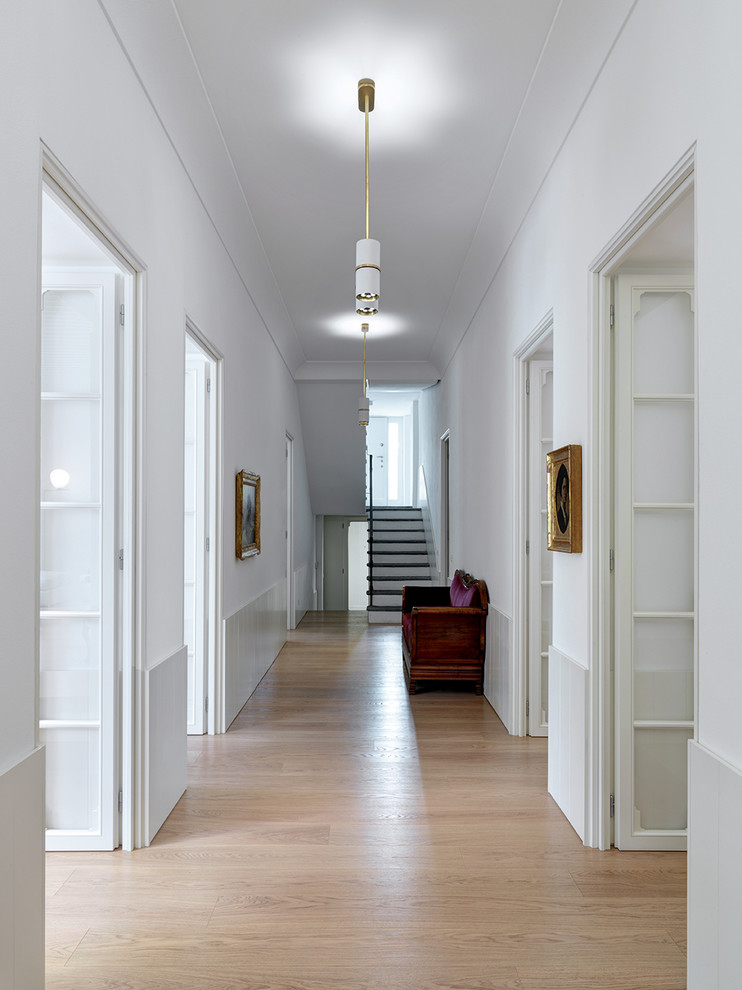 Photo of a large contemporary hallway with white walls, light hardwood floors and beige floor.