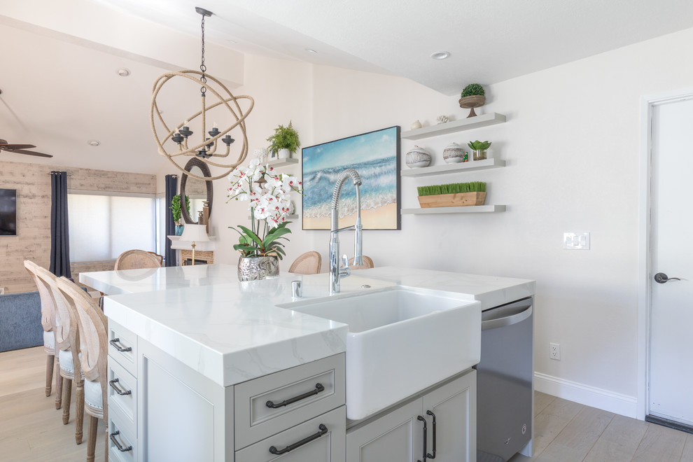 Mid-sized trendy u-shaped light wood floor and brown floor open concept kitchen photo in Orange County with a farmhouse sink, recessed-panel cabinets, gray cabinets, quartz countertops, white backsplash, marble backsplash, stainless steel appliances, an island and white countertops