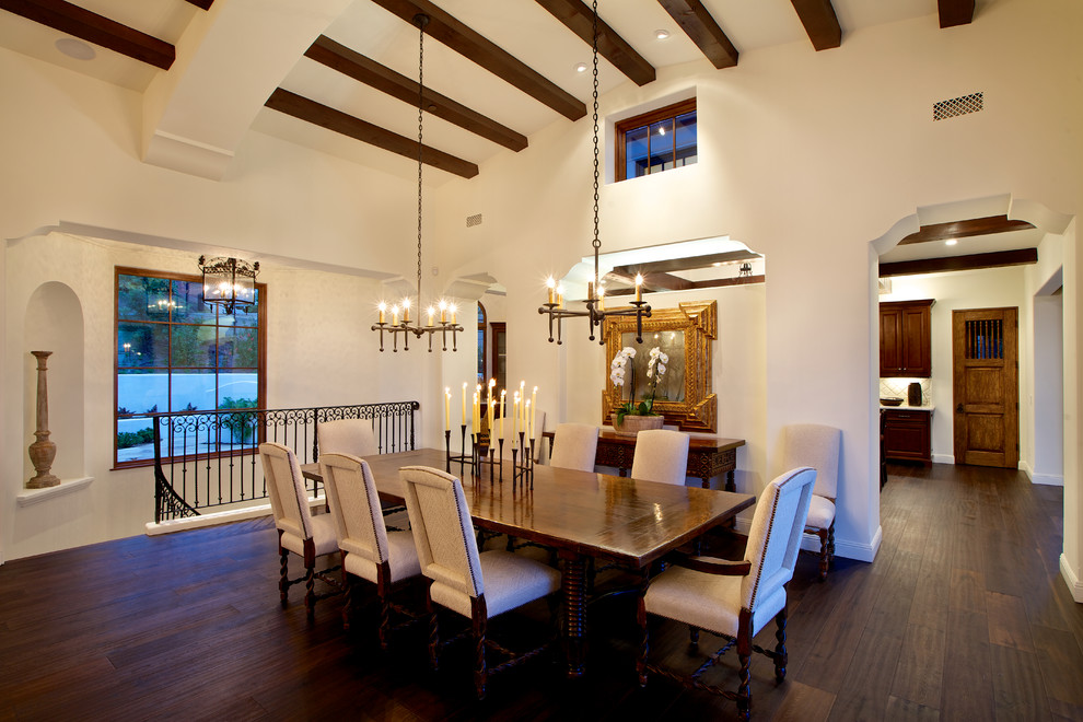 Photo of a mid-sized mediterranean open plan dining in San Diego with white walls, dark hardwood floors, a hanging fireplace and brown floor.