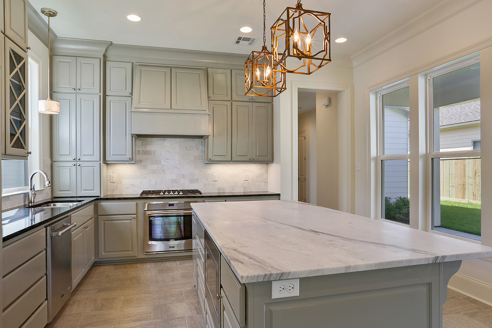 Photo of a mid-sized transitional kitchen in New Orleans with granite benchtops, with island, raised-panel cabinets, grey cabinets, vinyl floors, grey splashback, a drop-in sink, ceramic splashback, stainless steel appliances and beige floor.