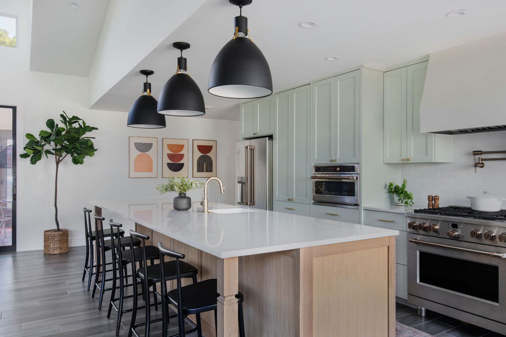 Inspiration for a transitional galley kitchen in Austin with an undermount sink, shaker cabinets, green cabinets, white splashback, stainless steel appliances, with island, grey floor and white benchtop.