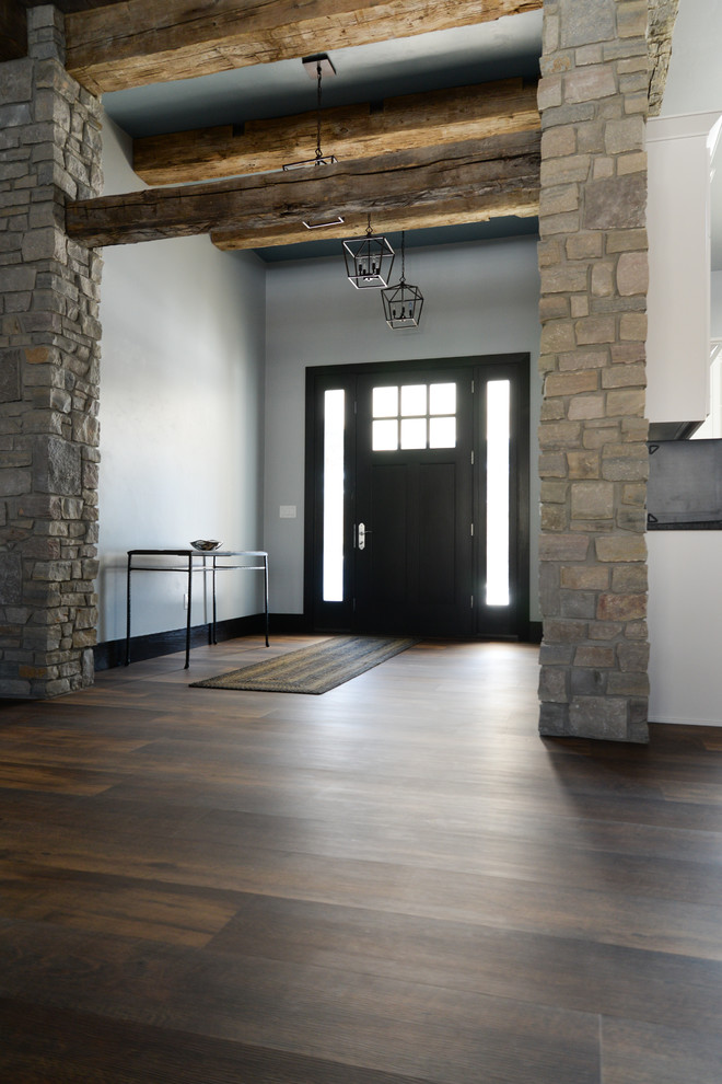 Example of a brown floor and vinyl floor pivot front door design with a dark wood front door and white walls