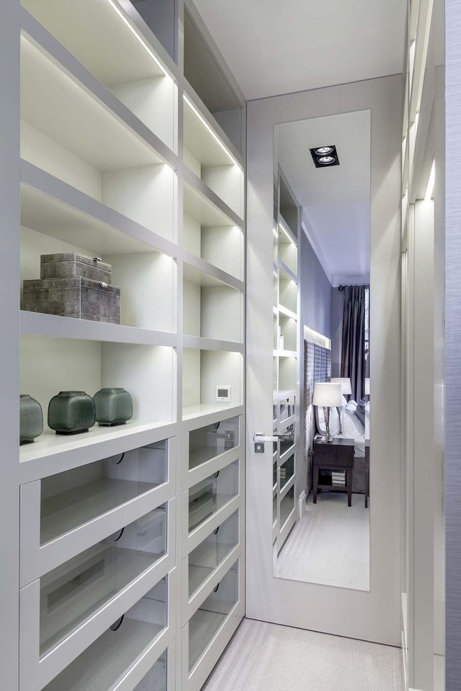 Inspiration for a mid-sized contemporary gender-neutral walk-in wardrobe in London with glass-front cabinets, grey cabinets, carpet and grey floor.