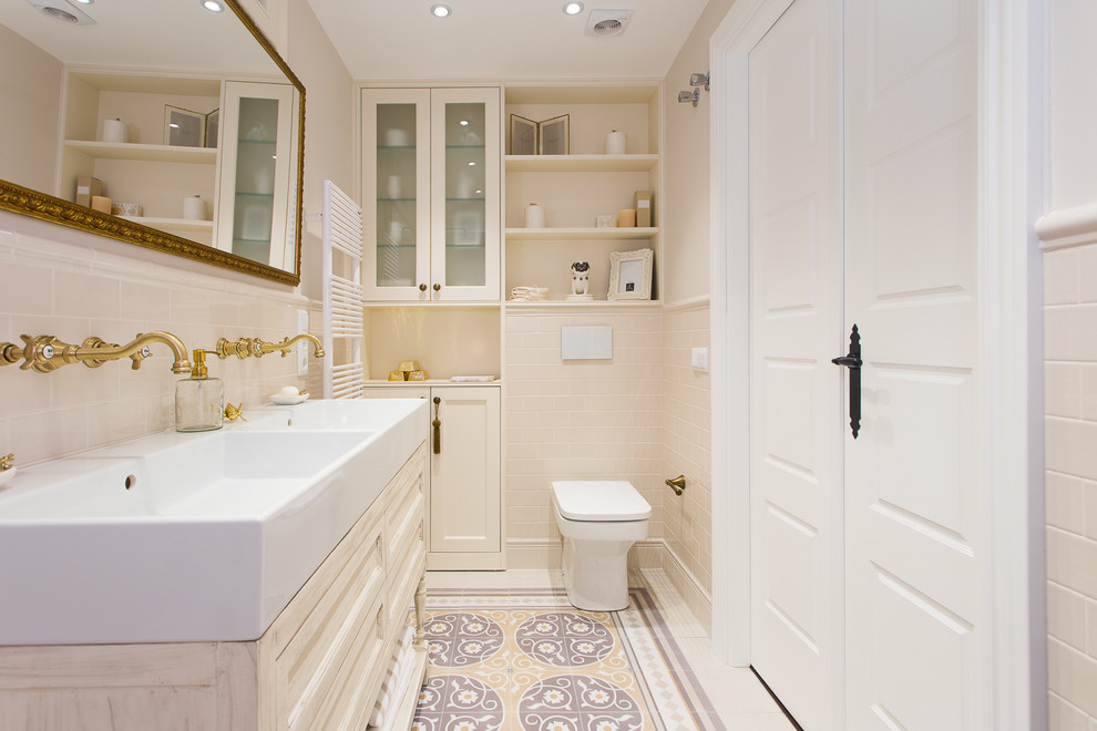 Inspiration for a mid-sized traditional 3/4 bathroom in Barcelona with white cabinets, a one-piece toilet, beige walls, porcelain tile, mosaic tile floors, a vessel sink, wood benchtops and beige tile.