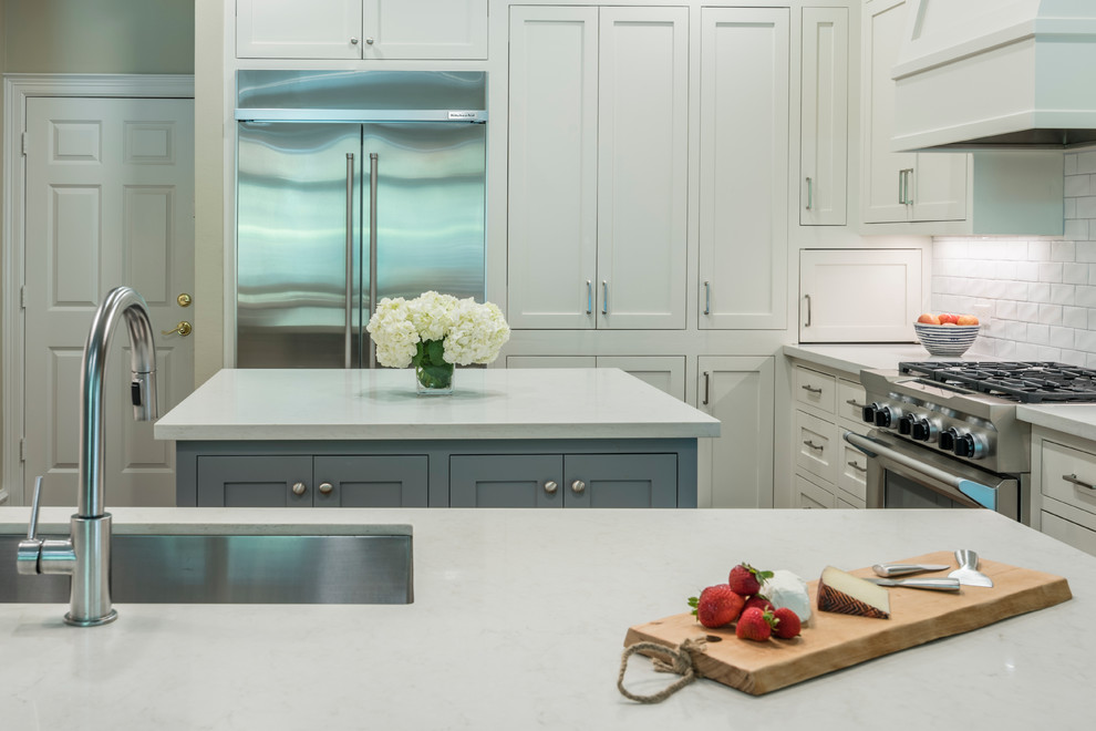 Open concept kitchen - mid-sized transitional medium tone wood floor open concept kitchen idea in Houston with an undermount sink, shaker cabinets, white cabinets, quartz countertops, white backsplash, subway tile backsplash, stainless steel appliances and an island