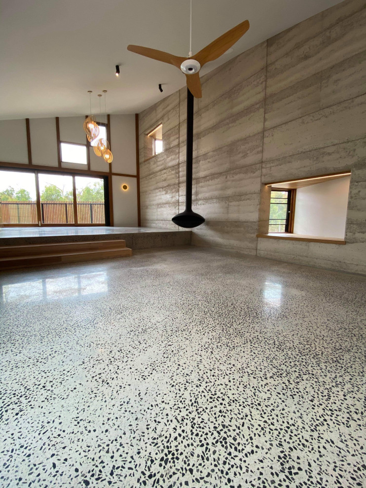 Стильный дизайн: открытая гостиная комната среднего размера в стиле лофт с серыми стенами, бетонным полом, подвесным камином и серым полом - последний тренд