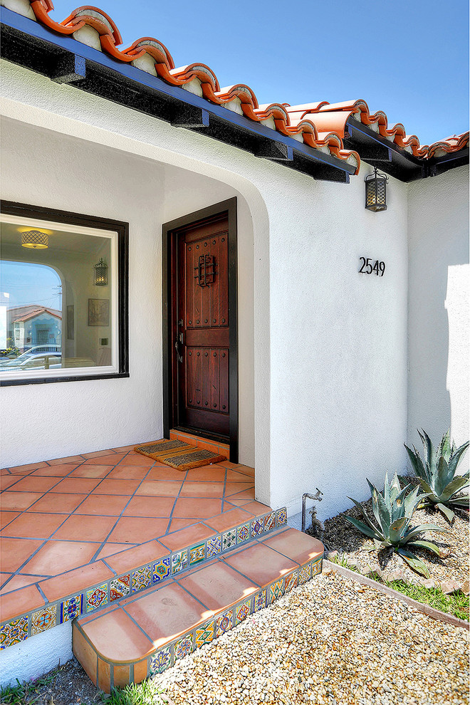 This is an example of a mediterranean front door in Los Angeles with terra-cotta floors and a single front door.