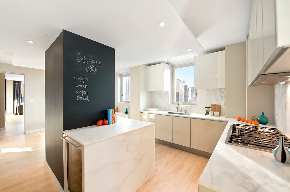 This is an example of a modern kitchen in New York with flat-panel cabinets, white cabinets and white splashback.
