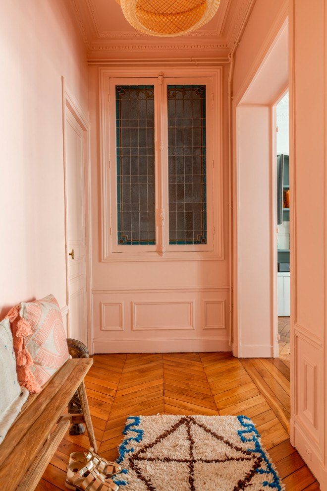 パリにあるお手頃価格の中くらいなコンテンポラリースタイルのおしゃれな玄関ホール (ピンクの壁、無垢フローリング、茶色い床、三角天井) の写真