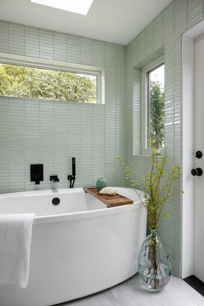 This is an example of a small modern ensuite wet room bathroom in Seattle with flat-panel cabinets, light wood cabinets, a freestanding bath, a bidet, green tiles, glass tiles, white walls, cement flooring, a vessel sink, quartz worktops, grey floors, a hinged door, white worktops, an enclosed toilet, double sinks, a built in vanity unit and a vaulted ceiling.