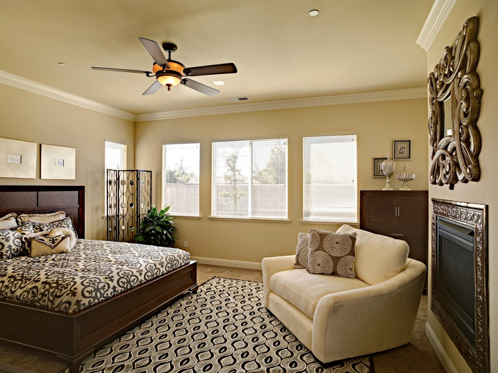 Photo of a mid-sized modern master bedroom in Other with beige walls, carpet, a standard fireplace, a metal fireplace surround and beige floor.