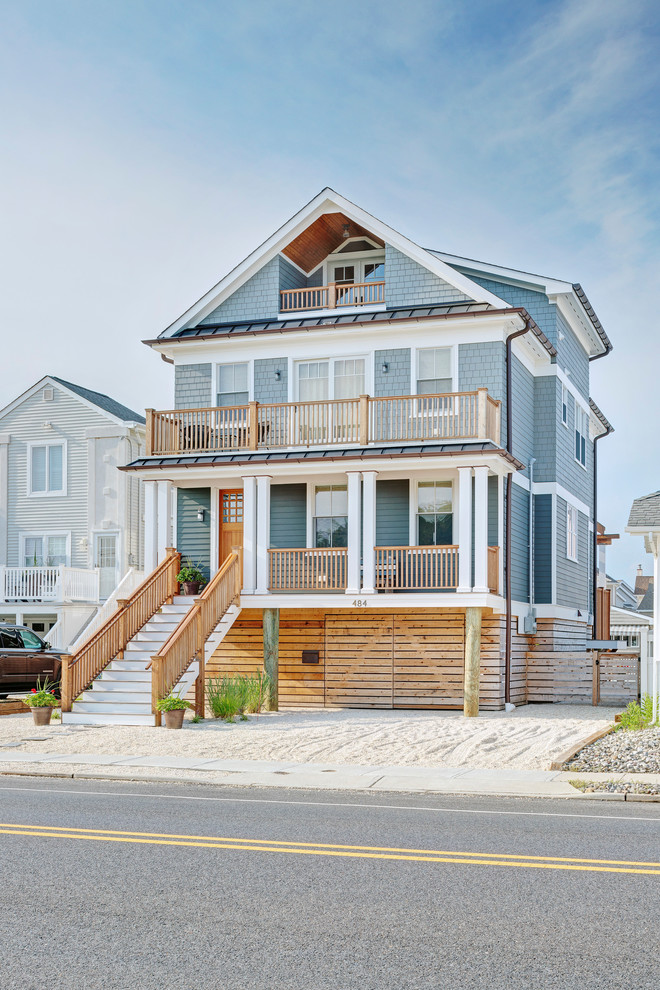 Photo of a beach style three-storey grey house exterior in Other with a gable roof and a metal roof.