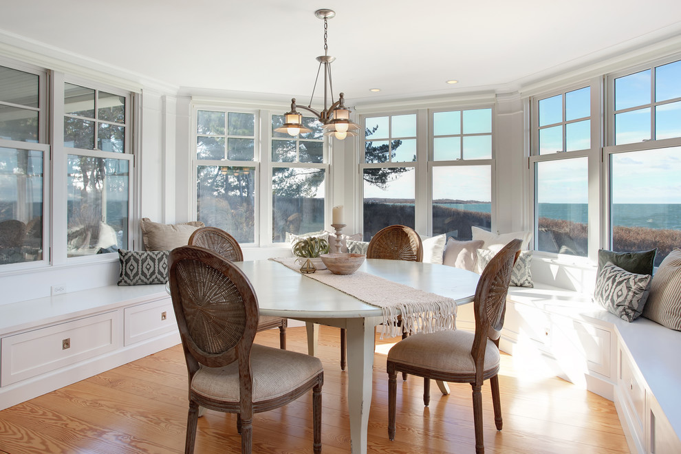 Photo of a beach style dining room in Boston with white walls, medium hardwood floors and brown floor.
