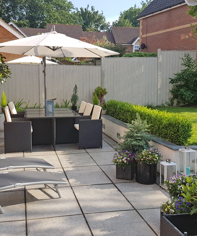Design ideas for a mid-sized contemporary backyard patio in Hertfordshire with natural stone pavers.