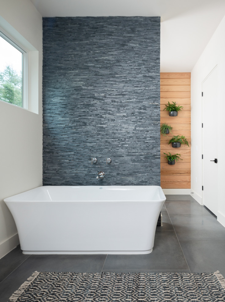 This is an example of a mid-sized contemporary master bathroom in Austin with flat-panel cabinets, beige cabinets, a freestanding tub, a shower/bathtub combo, a one-piece toilet, grey walls, cement tiles, a drop-in sink, grey floor, a hinged shower door, a shower seat, a double vanity, a floating vanity and wood walls.