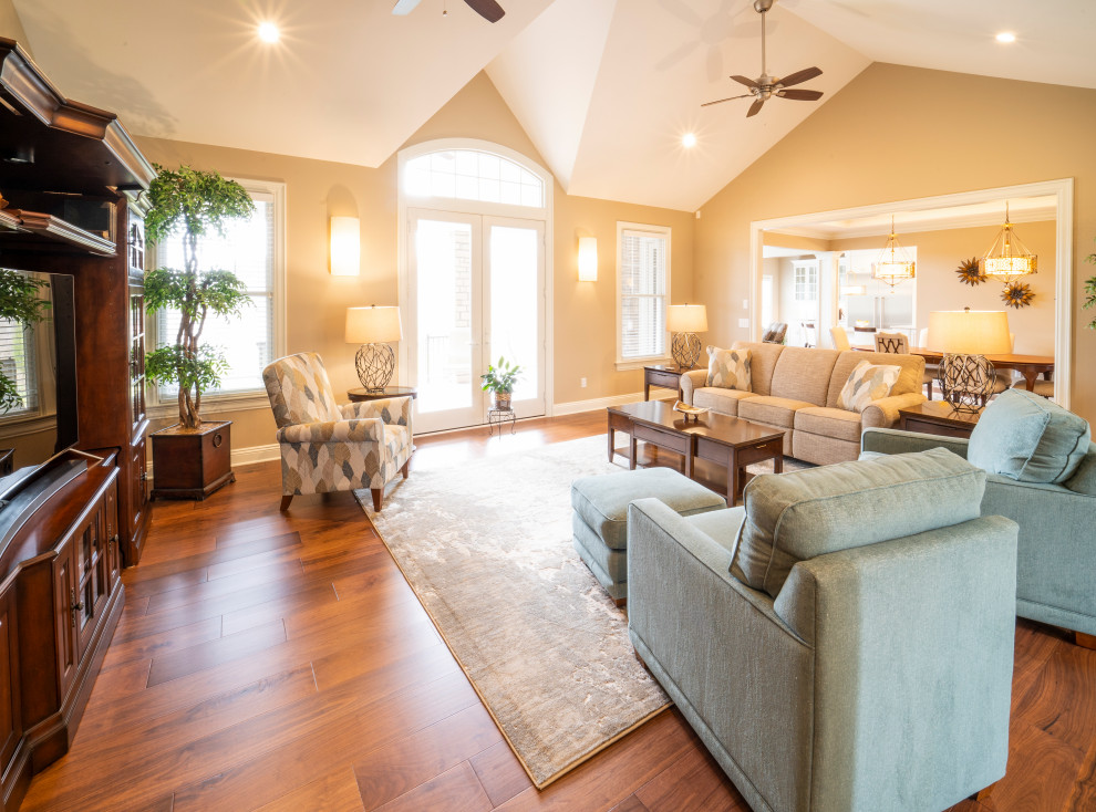 Immagine di un grande soggiorno classico aperto con pareti beige, pavimento in legno massello medio, pavimento marrone, soffitto a volta e pareti in legno