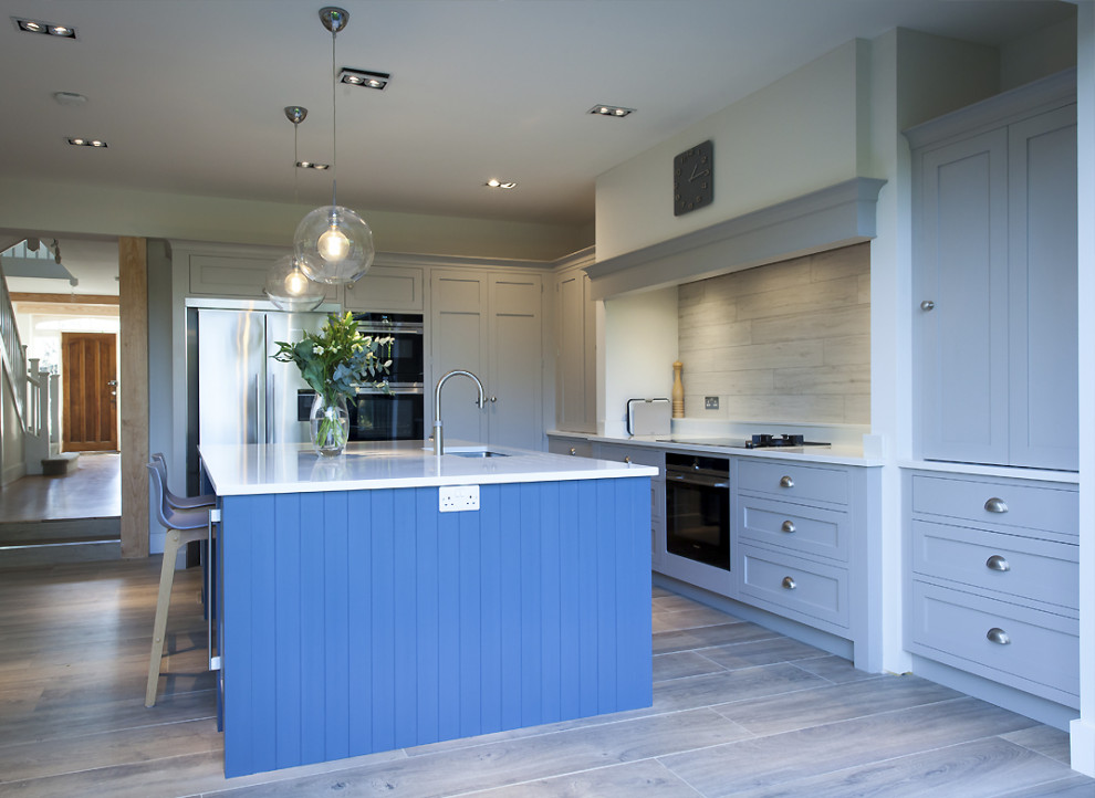 Mid-sized scandinavian l-shaped eat-in kitchen in Other with an undermount sink, shaker cabinets, grey cabinets, solid surface benchtops, beige splashback, ceramic splashback, black appliances, ceramic floors, with island, beige floor and white benchtop.