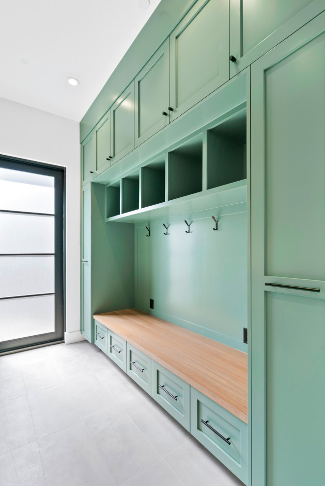This is an example of a mid-sized country single-wall utility room in San Francisco with shaker cabinets, green cabinets, grey walls, concrete floors, a side-by-side washer and dryer and grey floor.