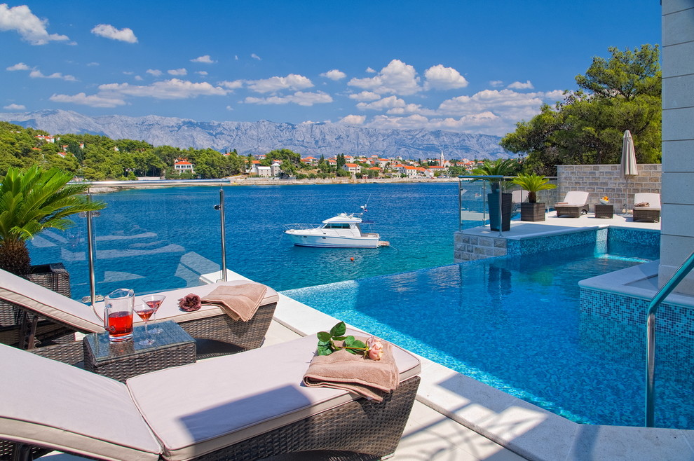 This is an example of a mediterranean backyard custom-shaped infinity pool in Other.