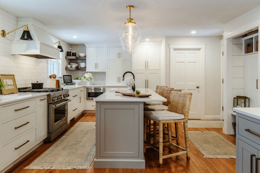 Photo of a transitional eat-in kitchen in Boston with white splashback, subway tile splashback, stainless steel appliances and with island.