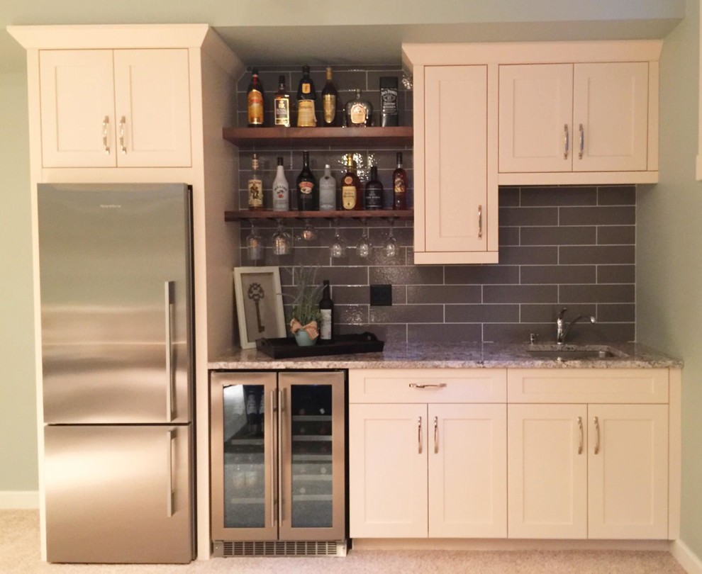 Inspiration for a mid-sized traditional single-wall wet bar in Vancouver with an undermount sink, beaded inset cabinets, white cabinets, granite benchtops, grey splashback, carpet, beige floor and multi-coloured benchtop.