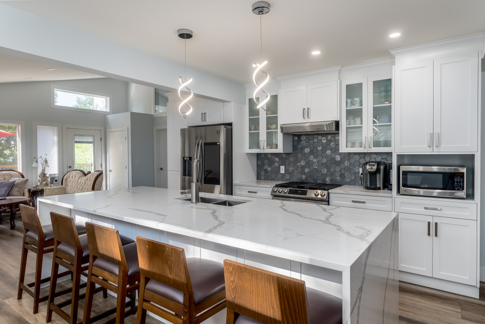 Example of a transitional kitchen design in Edmonton with shaker cabinets, white cabinets, quartzite countertops, gray backsplash, cement tile backsplash, stainless steel appliances, an island and white countertops