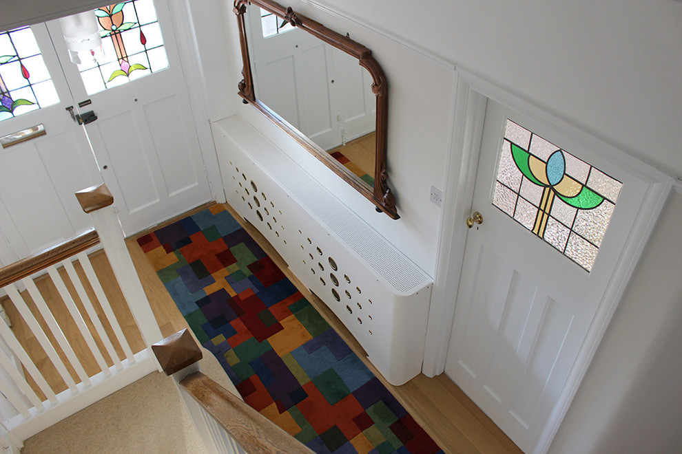 Photo of a large contemporary entry hall in Other with white walls, light hardwood floors, a single front door and a white front door.