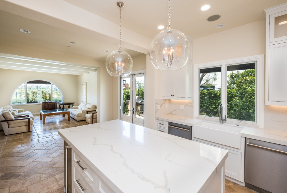 Enclosed kitchen - mid-sized transitional l-shaped porcelain tile and beige floor enclosed kitchen idea in Orange County with a farmhouse sink, recessed-panel cabinets, white cabinets, quartz countertops, white backsplash, marble backsplash, stainless steel appliances and an island