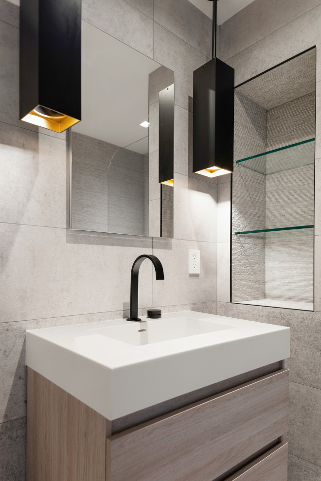 This is an example of a small modern 3/4 bathroom in New York with flat-panel cabinets, light wood cabinets, an alcove shower, gray tile, porcelain tile, a wall-mount sink, engineered quartz benchtops, a hinged shower door, white benchtops, a single vanity and a floating vanity.