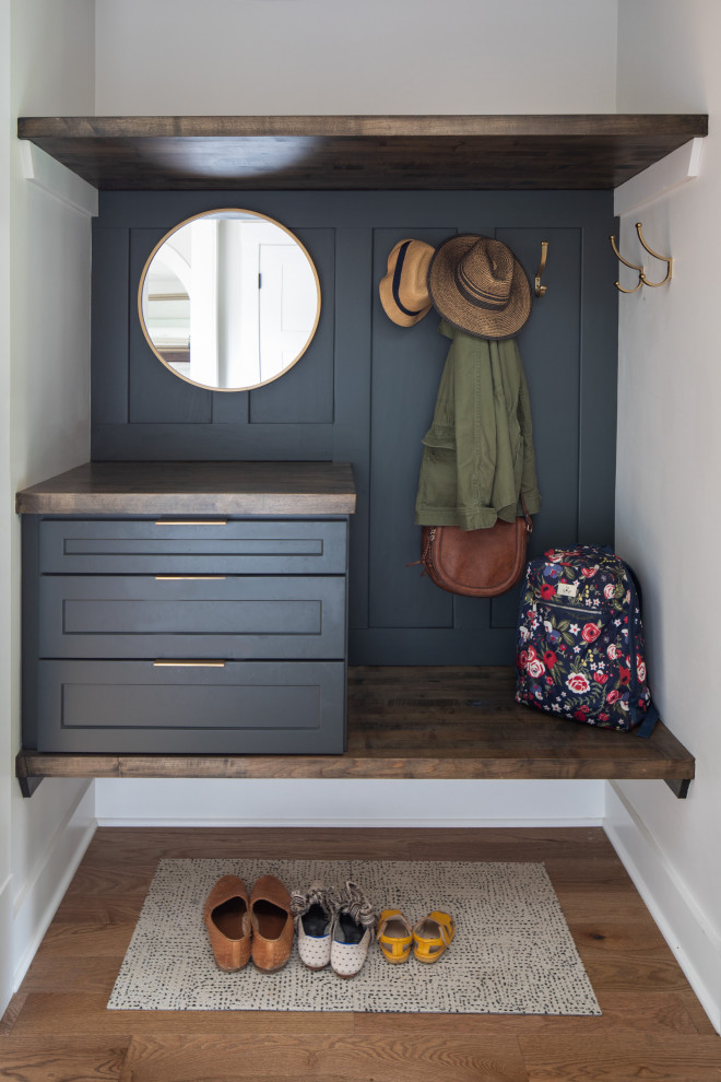 Example of a transitional medium tone wood floor and brown floor entryway design with white walls