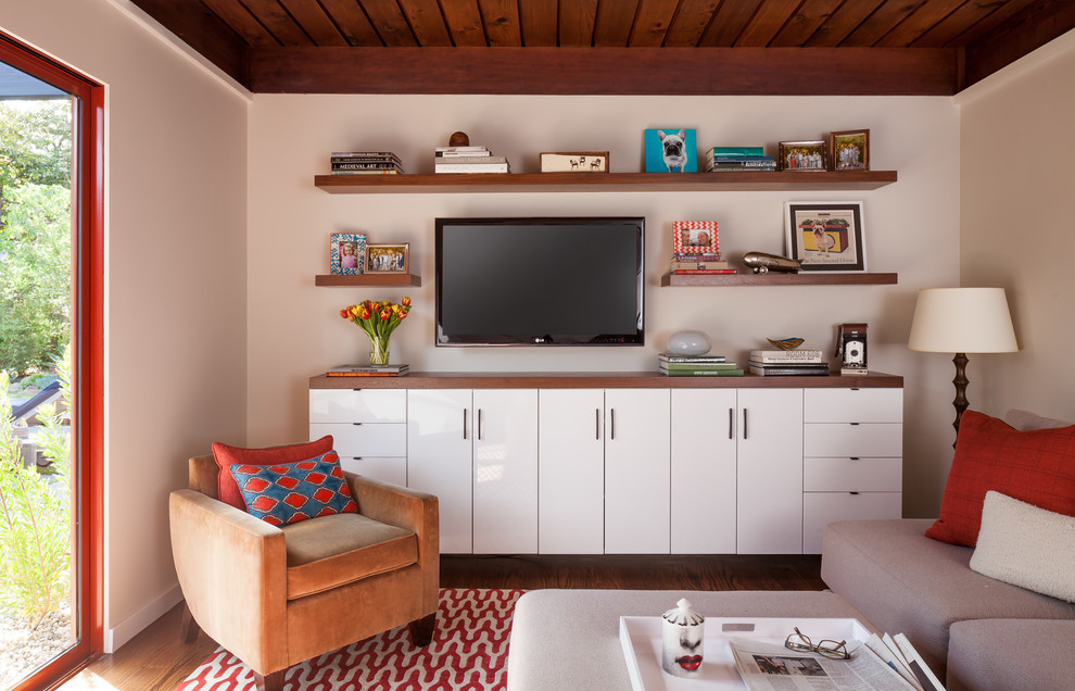 This is an example of a small midcentury open concept home theatre in San Francisco with white walls, dark hardwood floors and a wall-mounted tv.