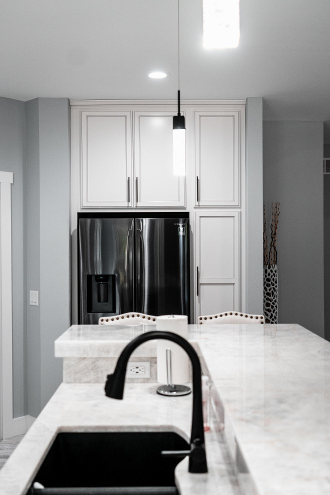 Inspiration for a huge transitional l-shaped laminate floor, gray floor and tray ceiling open concept kitchen remodel with an undermount sink, flat-panel cabinets, white cabinets, quartz countertops, gray backsplash, ceramic backsplash, black appliances and an island