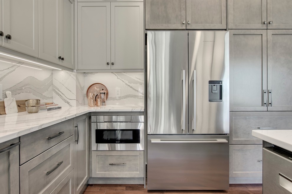 Example of a large transitional u-shaped dark wood floor and brown floor eat-in kitchen design in Calgary with an undermount sink, recessed-panel cabinets, gray cabinets, quartzite countertops, white backsplash, stone slab backsplash, stainless steel appliances, an island and white countertops