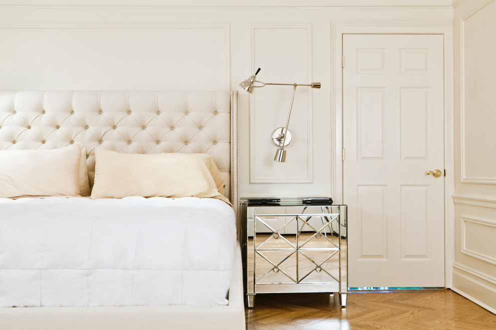 ニューヨークにある中くらいなトランジショナルスタイルのおしゃれな主寝室 (白い壁、淡色無垢フローリング、標準型暖炉、木材の暖炉まわり、茶色い床、板張り壁)