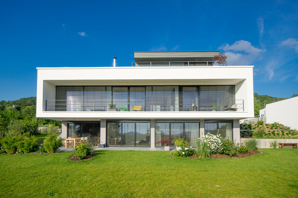 This is an example of a large contemporary three-storey stucco white exterior in Nuremberg with a flat roof.