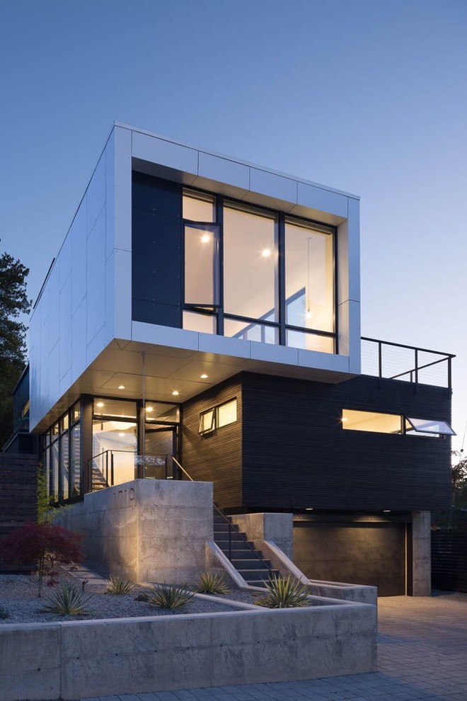 Photo of a contemporary two-storey black house exterior in Seattle with mixed siding and a flat roof.