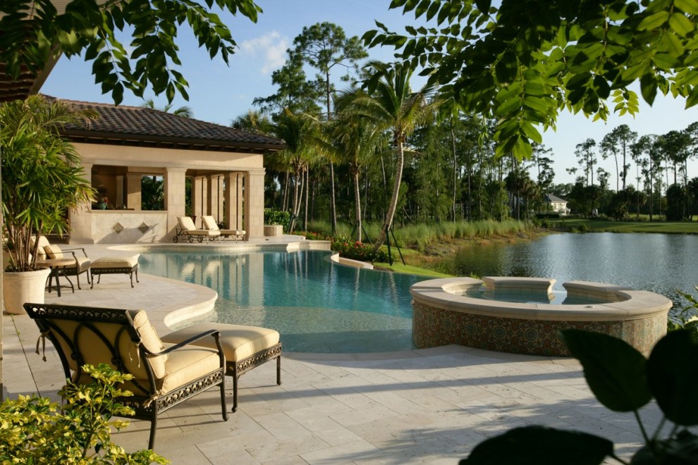 Photo of a mediterranean backyard custom-shaped pool in Miami with natural stone pavers.