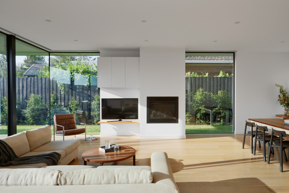 Design ideas for a contemporary open plan living room in Melbourne with white walls, light hardwood flooring, a standard fireplace, a plastered fireplace surround and a freestanding tv.