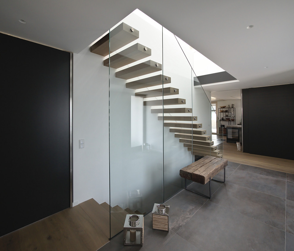 Idée de décoration pour un escalier design avec des marches en bois et un garde-corps en verre.
