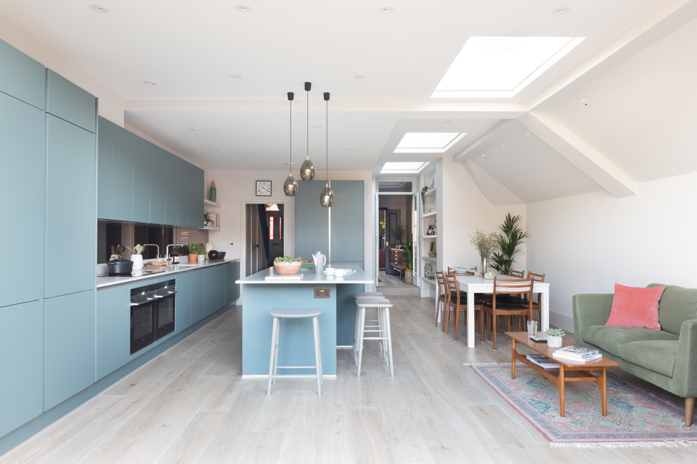 Inspiration for a mid-sized contemporary single-wall eat-in kitchen in London with an undermount sink, flat-panel cabinets, blue cabinets, mirror splashback, panelled appliances, with island and beige floor.