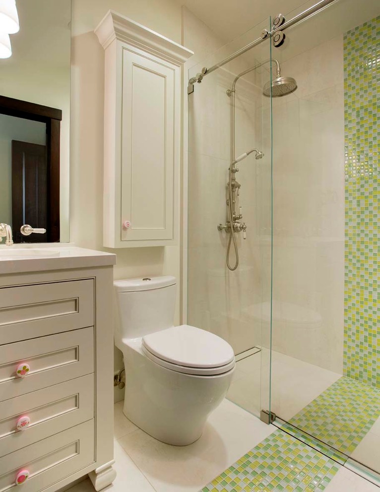 This is an example of a small country kids bathroom in San Francisco with furniture-like cabinets, white cabinets, a curbless shower, a one-piece toilet, multi-coloured tile, porcelain floors, an undermount sink, engineered quartz benchtops, glass sheet wall and white walls.