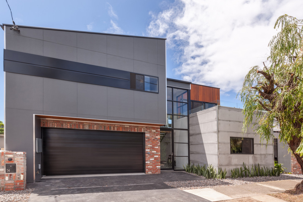 Photo of a large industrial three-storey grey house exterior in Newcastle - Maitland with concrete fiberboard siding, a flat roof and a metal roof.