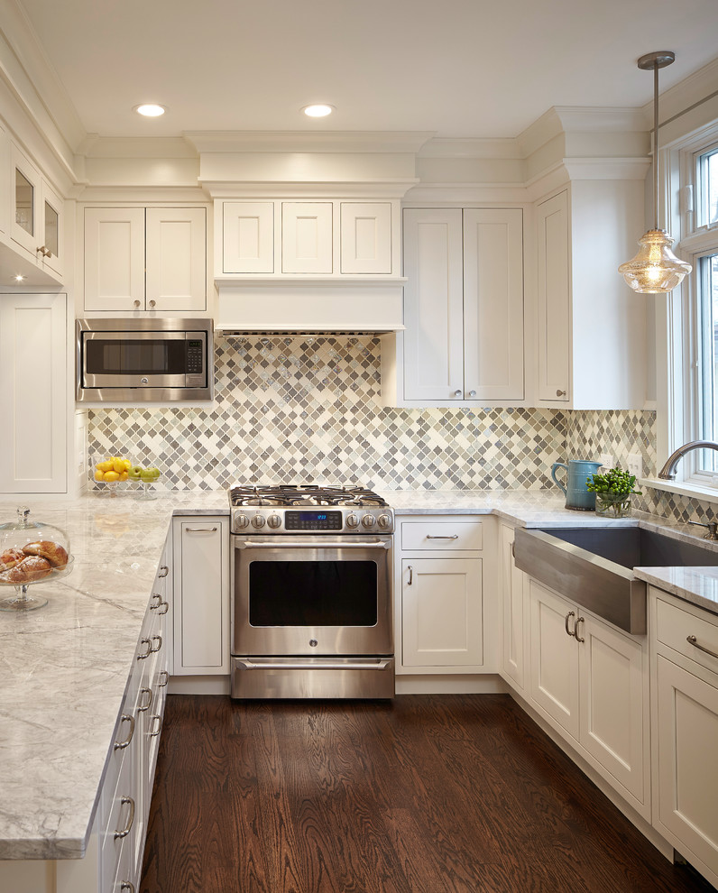 This is an example of a mid-sized transitional u-shaped separate kitchen in Chicago with a farmhouse sink, beaded inset cabinets, white cabinets, quartz benchtops, grey splashback, mosaic tile splashback, stainless steel appliances, dark hardwood floors and no island.