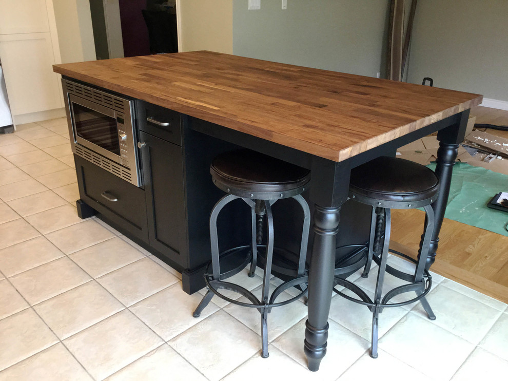Example of a mid-sized transitional l-shaped kitchen design in Ottawa with an undermount sink, shaker cabinets, dark wood cabinets, soapstone countertops, white backsplash, ceramic backsplash, stainless steel appliances and an island