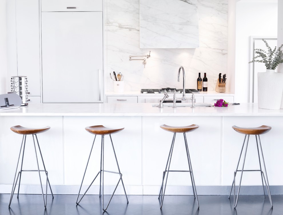 Example of a trendy galley kitchen design in New York with white backsplash, stone slab backsplash, an island, flat-panel cabinets, white cabinets and white walls