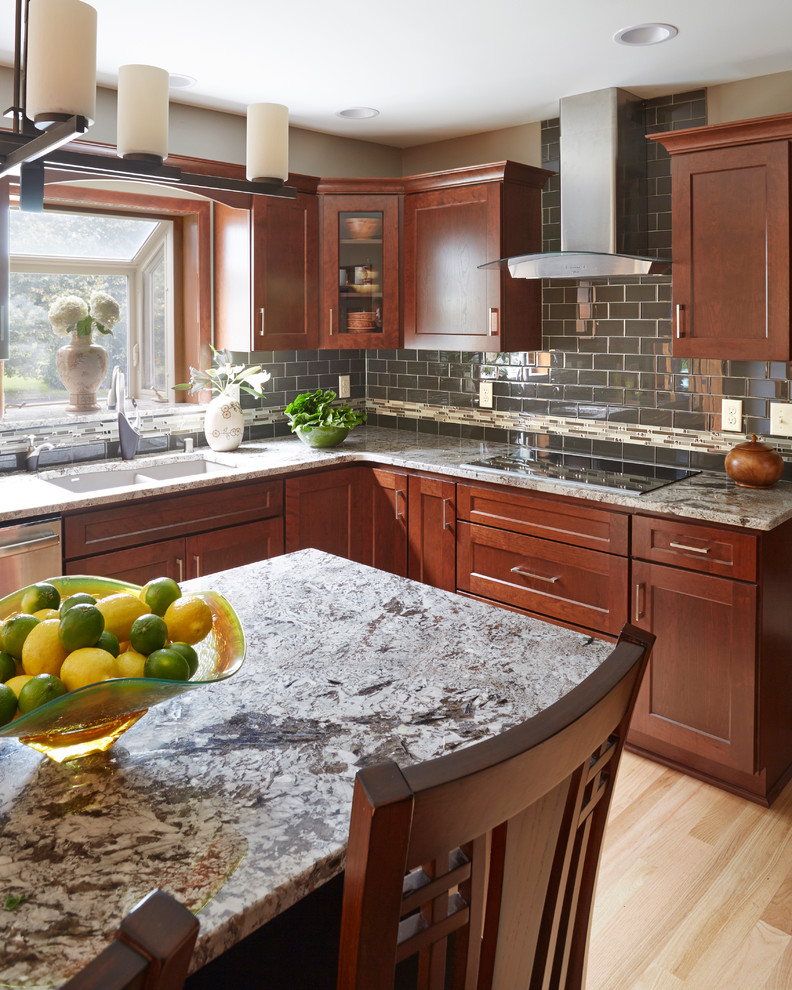 Inspiration for a large transitional l-shaped light wood floor open concept kitchen remodel in Milwaukee with an undermount sink, shaker cabinets, dark wood cabinets, granite countertops, gray backsplash, subway tile backsplash, stainless steel appliances and an island