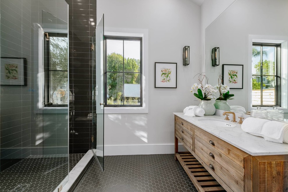 Photo of a mid-sized country bathroom in Los Angeles with an alcove shower, grey walls, an undermount sink, quartzite benchtops, a hinged shower door, white benchtops, medium wood cabinets, black tile, black floor and recessed-panel cabinets.