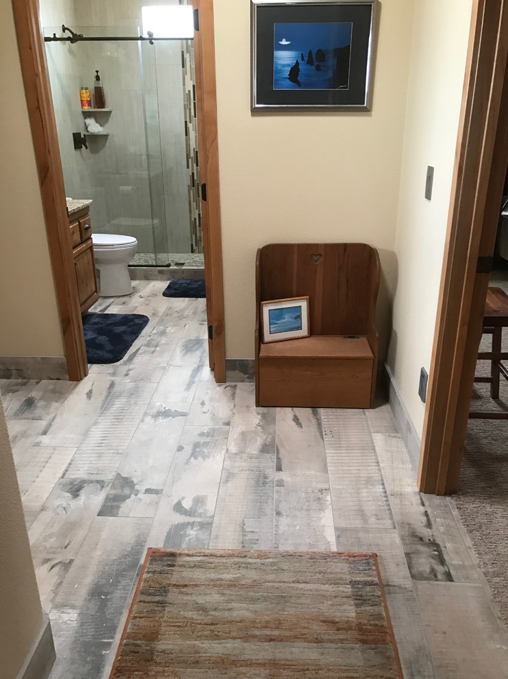 Small mountain style 3/4 beige tile and porcelain tile light wood floor and brown floor alcove shower photo with raised-panel cabinets, dark wood cabinets, a two-piece toilet, beige walls, an undermount sink and granite countertops