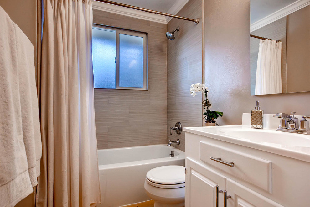 This is an example of a contemporary bathroom in Albuquerque with raised-panel cabinets, white cabinets, a drop-in tub, a shower/bathtub combo, brown walls, an integrated sink and solid surface benchtops.