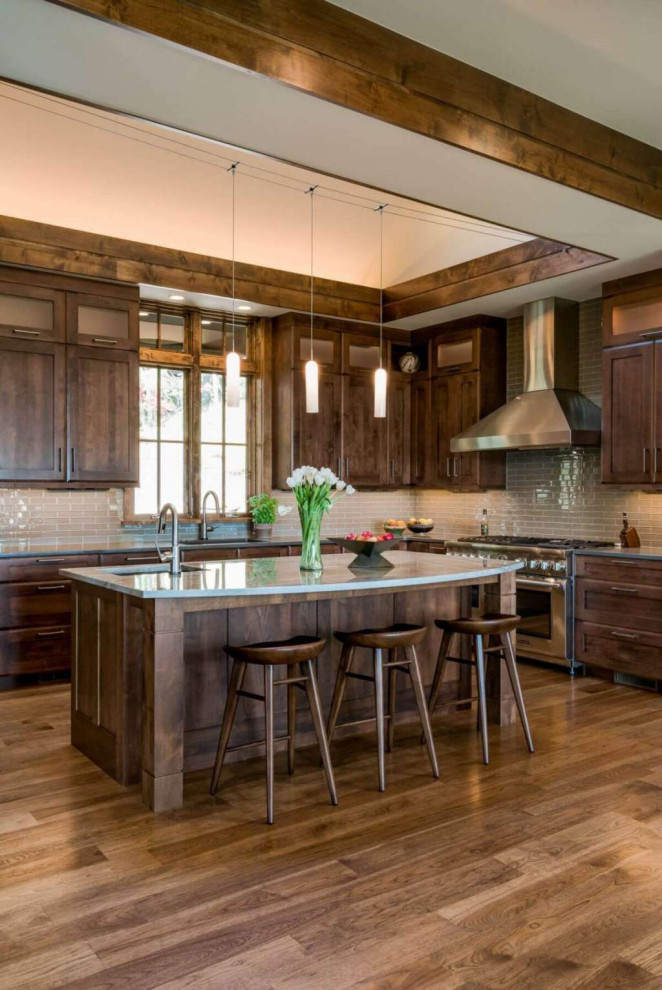 Inspiration for a large traditional l-shaped open plan kitchen in Columbus with an undermount sink, raised-panel cabinets, medium wood cabinets, quartzite benchtops, grey splashback, glass tile splashback, stainless steel appliances, medium hardwood floors, with island, brown floor and grey benchtop.